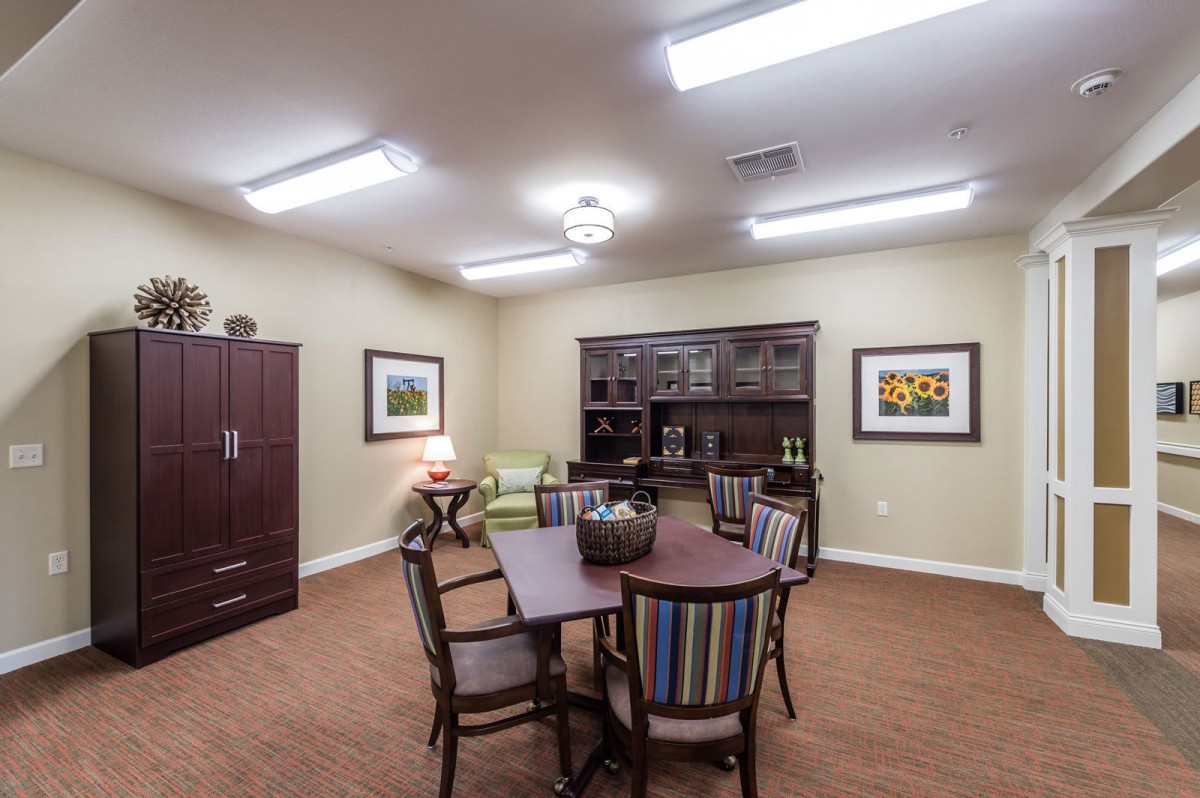 A well-lit office conference room with a round table, chairs, and bookshelves.