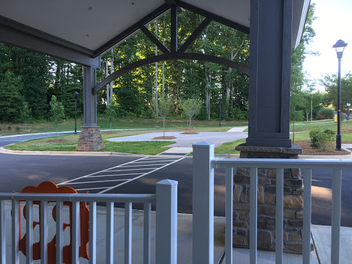 A serene view of a park entrance with a covered pavilion and lush greenery surrounding the area.