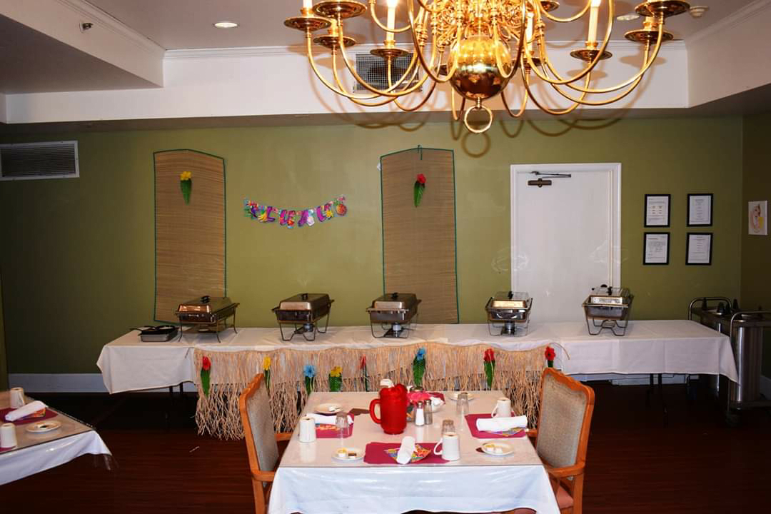 An elegantly set dining area with a buffet setup in the background and a chandelier overhead.