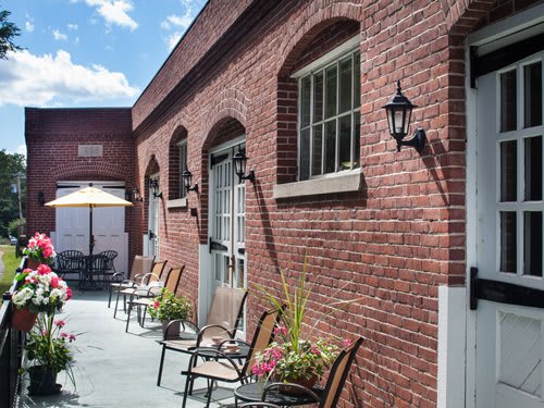 Outdoor patio area with brick walls, chairs, and plants on a sunny day.