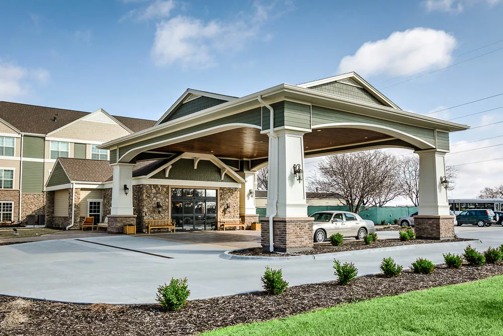 A modern building entrance with a covered carport and landscaped surroundings.