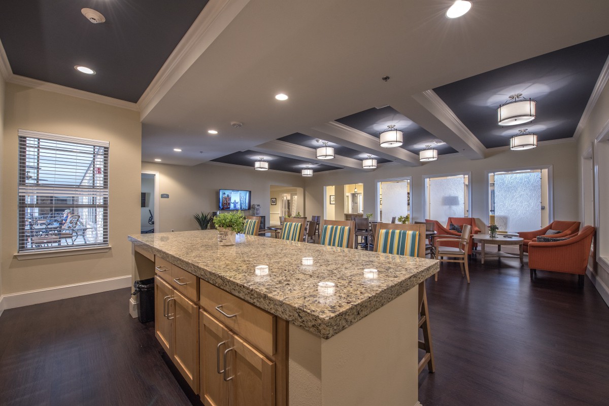A spacious kitchen with a granite countertop and adjacent dining area, featuring modern lighting and ample seating.