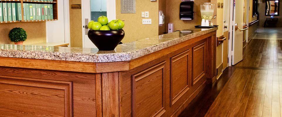 A hotel reception desk with a bowl of green apples.