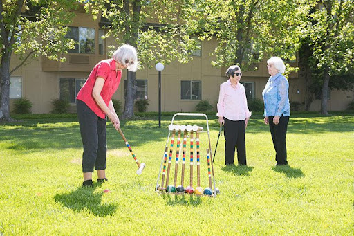 Seniors enjoying a game of croquet in the sun.