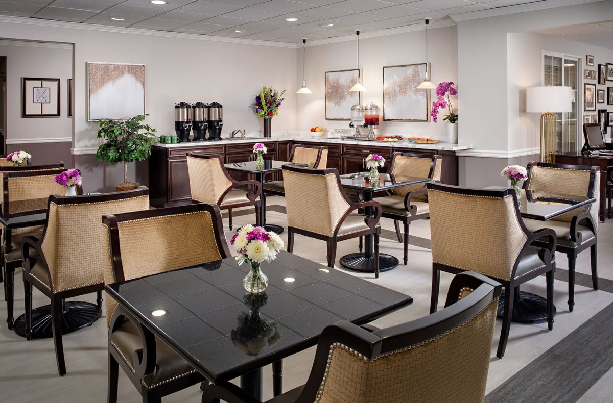 A cozy cafe interior with neatly arranged tables and chairs, adorned with floral decorations.