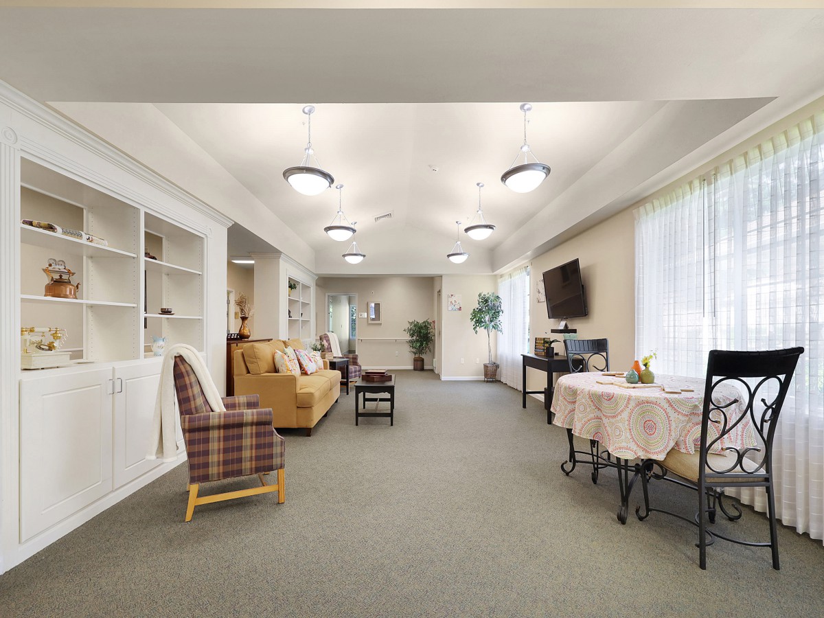 A spacious living room featuring comfortable seating, a TV, and bookshelves.