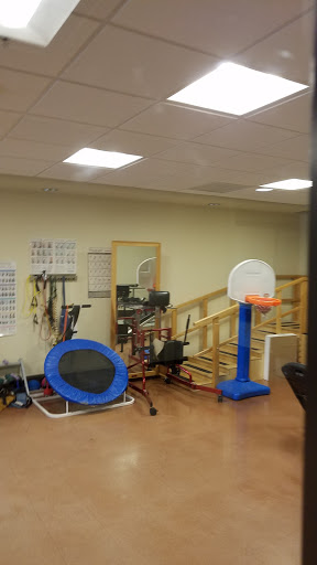 A well-equipped rehabilitation gym featuring a trampoline and a basketball hoop.
