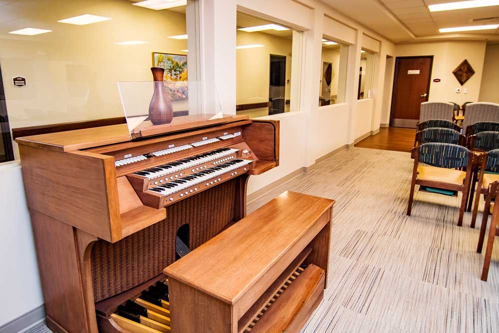 A wooden organ is placed in a well-lit music room with modern decor.