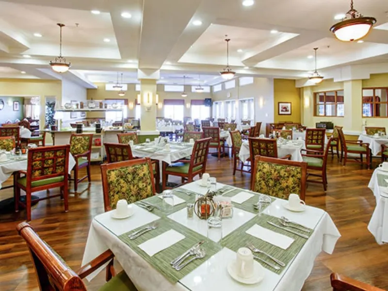 A spacious and elegantly furnished restaurant dining area with neatly arranged tables and chairs.