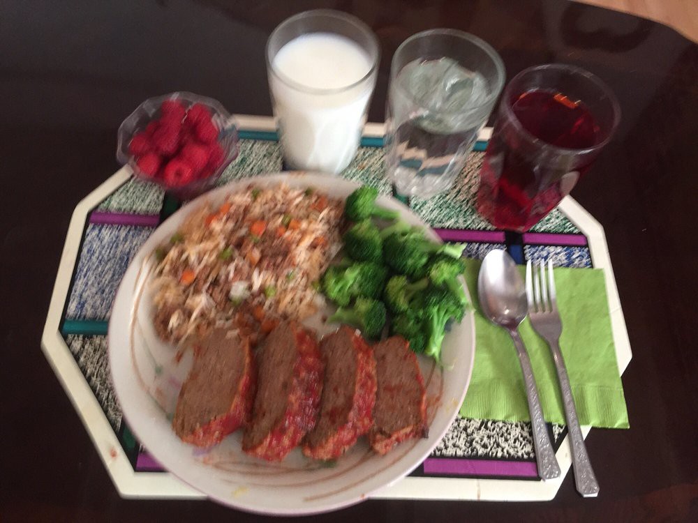 A well-balanced meal featuring meatloaf, broccoli, coleslaw, and raspberries served with milk, juice, and water.