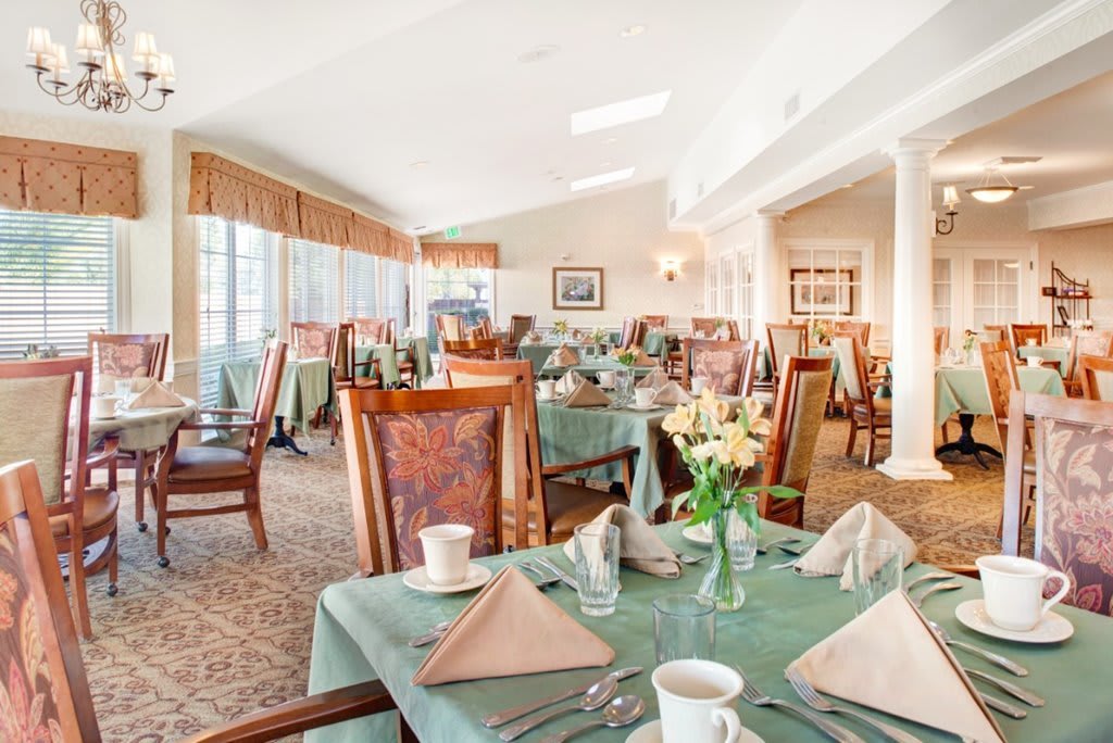 An elegantly set dining room with neatly arranged tables and chairs in a well-lit interior.