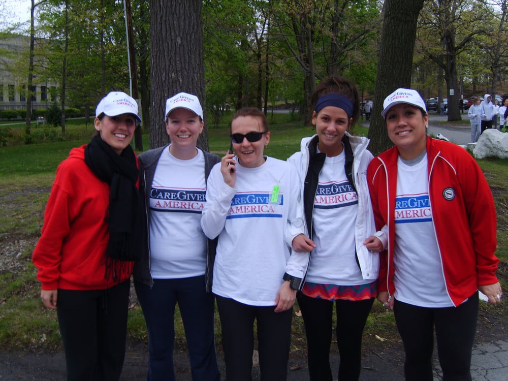A group of people poses together outdoors wearing casual clothing and hats.
