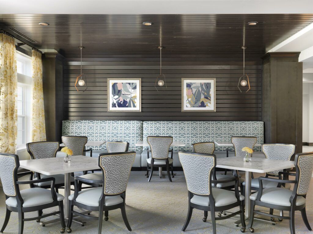 A modern restaurant dining area with neatly arranged tables and chairs, accented by framed pictures and chic lighting.