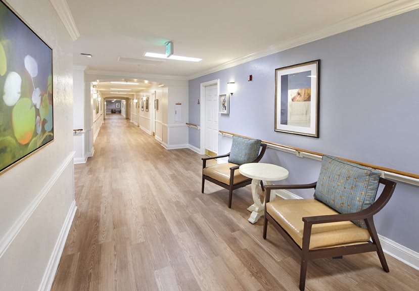 A clean and well-lit hallway in a healthcare facility with seating and artwork on the walls.