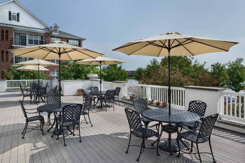 A spacious outdoor patio featuring tables and chairs with umbrellas, surrounded by greenery.