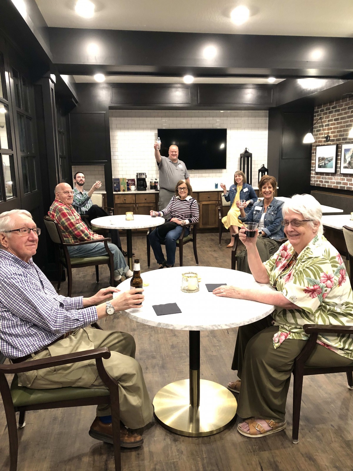 A group of people enjoying a social gathering indoors, raising their drinks in celebration.