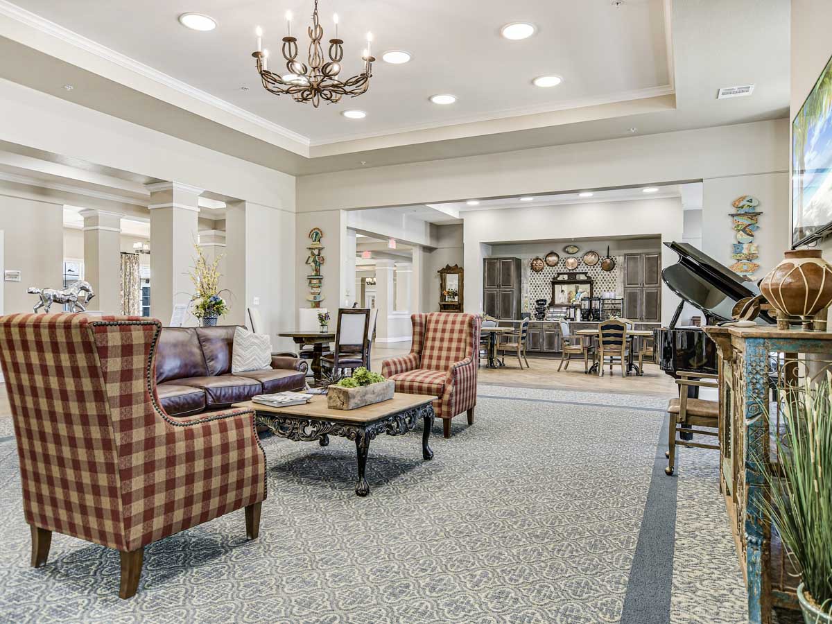 A spacious and elegantly designed living room with comfortable seating, a chandelier, and a grand piano.