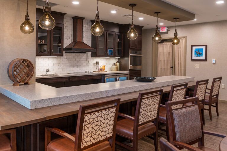 A modern kitchen with a bar area featuring pendant lights and wooden cabinetry.