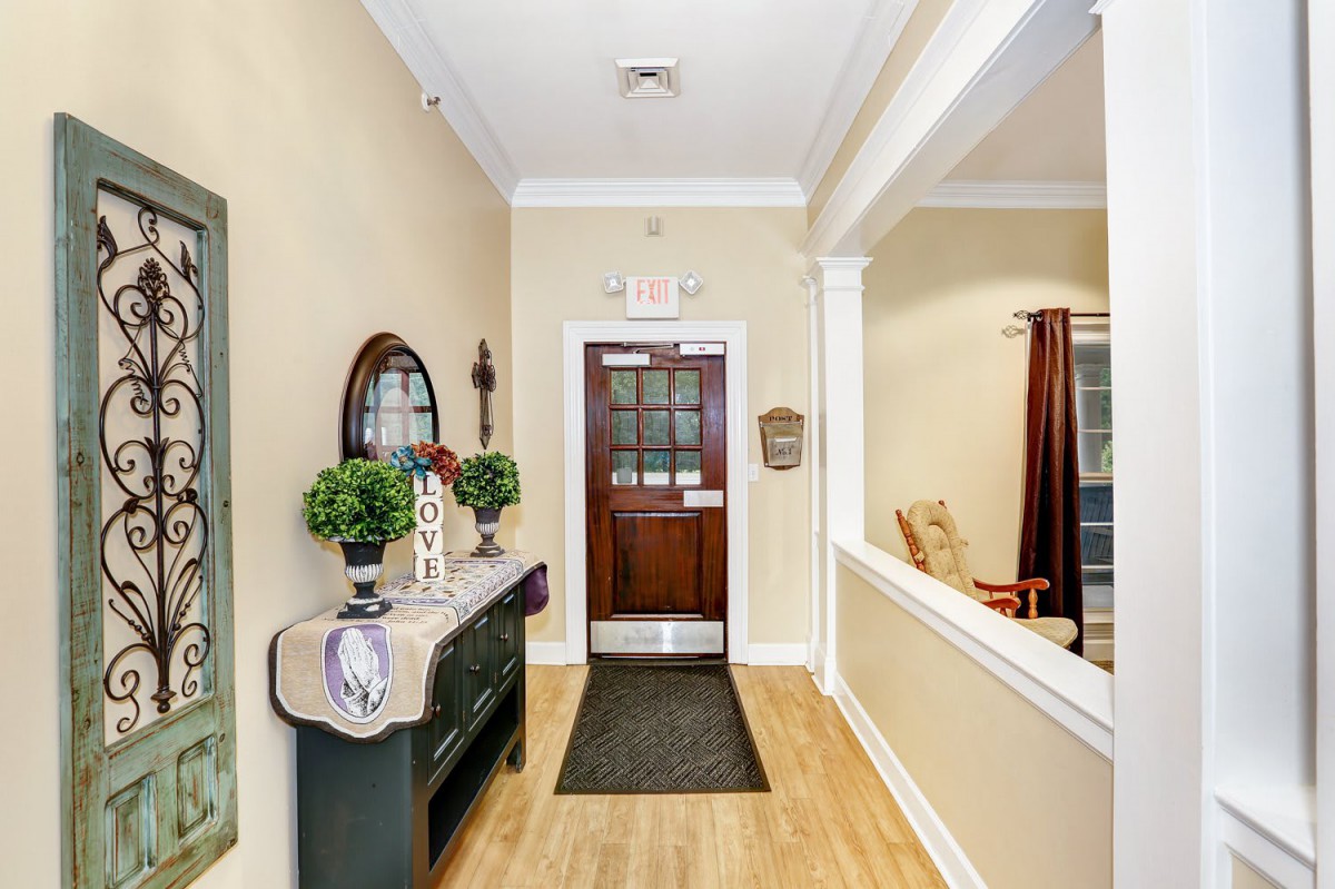 A welcoming entrance hallway decorated with greenery and a mirror, leading to a wooden door.