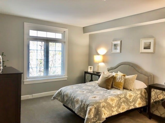 A cozy bedroom with a large window and neutral-toned decor.