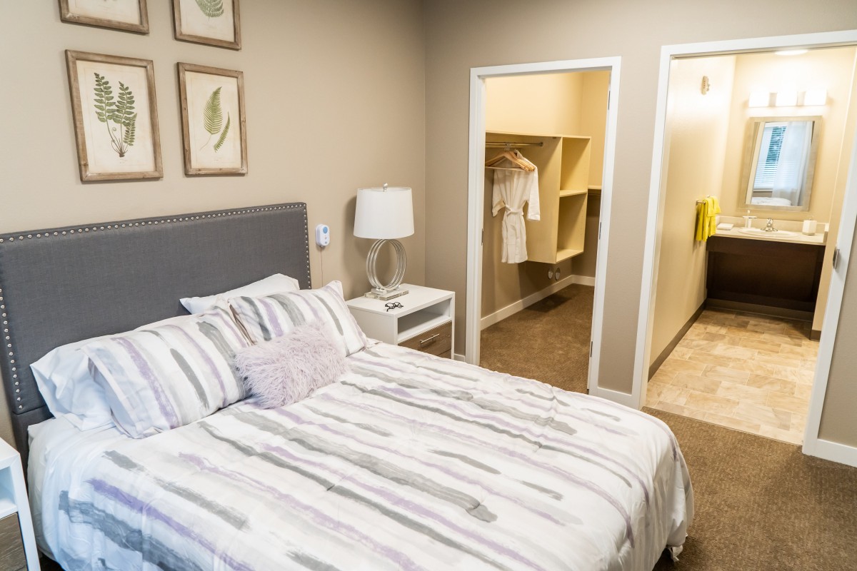 A cozy bedroom with a neatly made bed, wall art, and an open closet.
