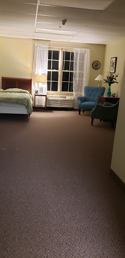 A cozy hotel room featuring a neatly made bed, a plush armchair, and a bright window.