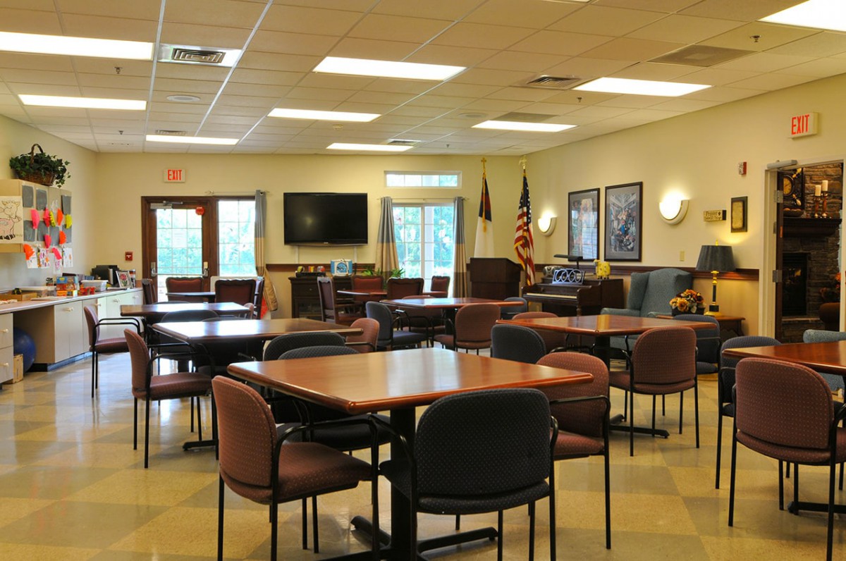 A spacious meeting room with multiple tables, chairs, a TV, and flags.
