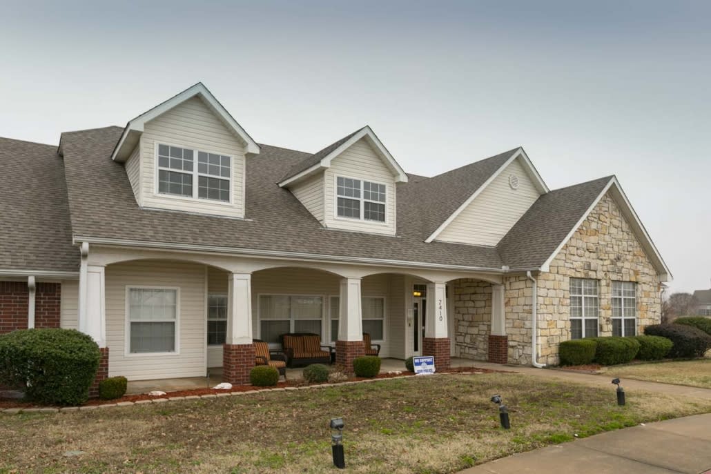 A two-story suburban house with a porch and brick features.