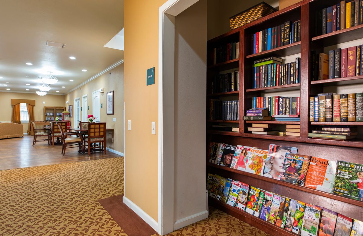 A cozy library corner with bookshelves and magazines along a carpeted hallway.