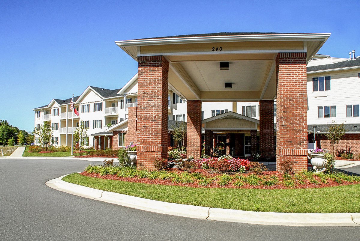 A residential building with a large brick entrance and landscaped surroundings.