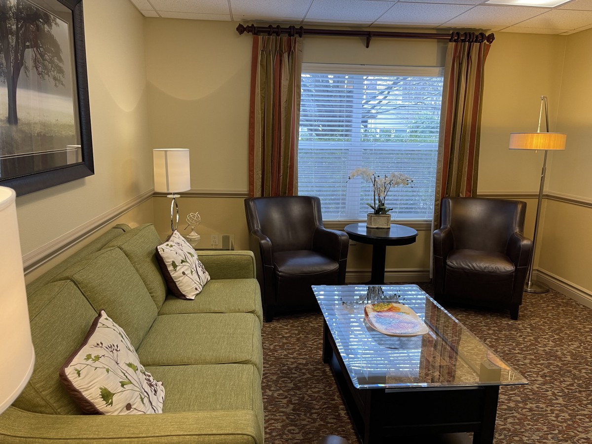 A cozy living room with a green couch, leather chairs, and a coffee table.