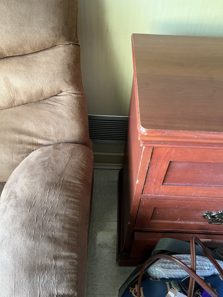 A plush sofa next to a wooden cabinet in a living room setting.