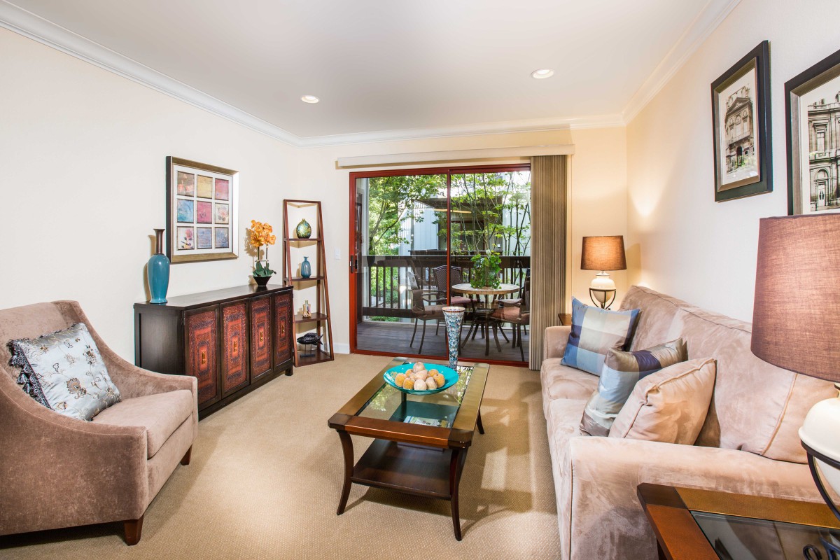 A cozy and well-decorated living room with comfortable seating, vibrant artwork, and ample lighting.