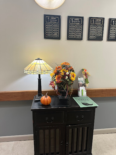 A cozy corner with seasonal decor featuring a lamp, autumn flowers, and a small pumpkin.
