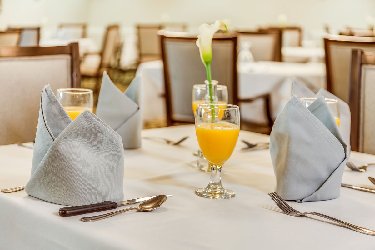 A formal dining table setting with orange juice and elegant decorations.