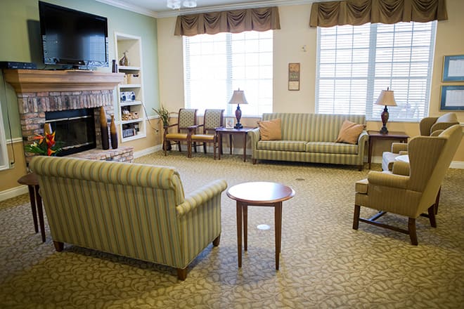 A cozy living room with sofas, chairs, a television, and large windows allowing natural light.