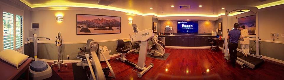 A well-lit gym room featuring modern exercise equipment and a warm ambiance.