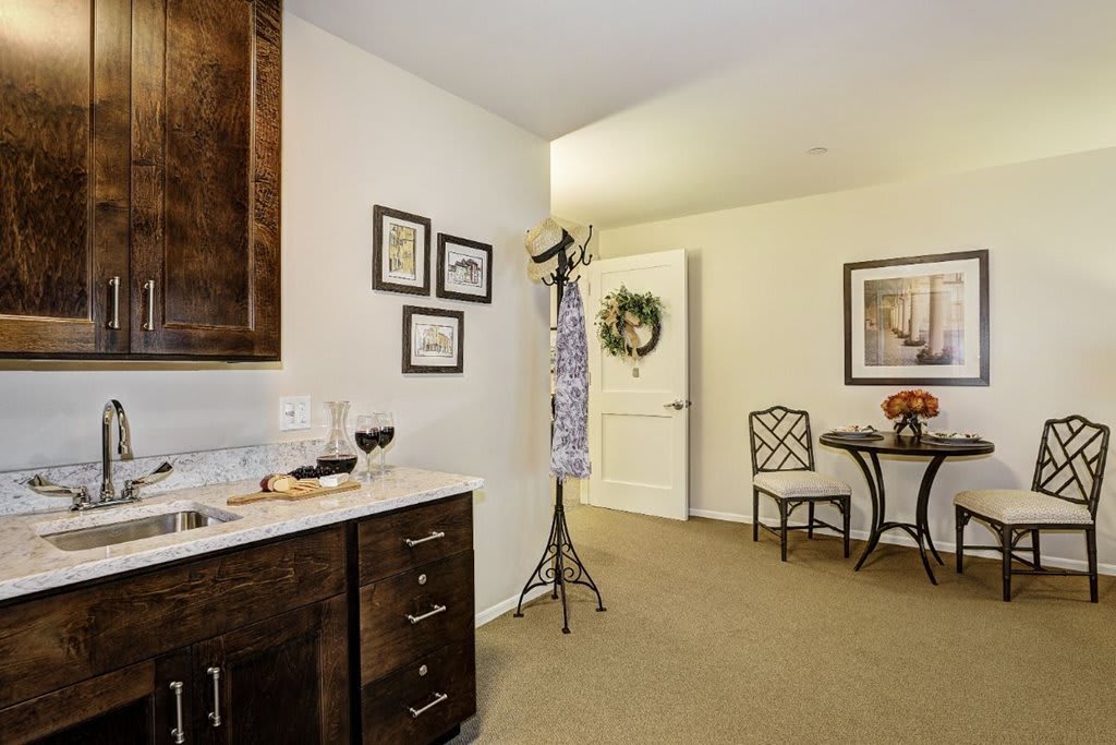 A cozy interior featuring a small dining area with a table and chairs, adjacent to a kitchenette with decorative artwork.