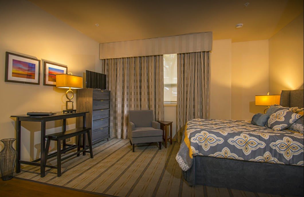 Cozy hotel room with a comfortable bed, desk, and chair.