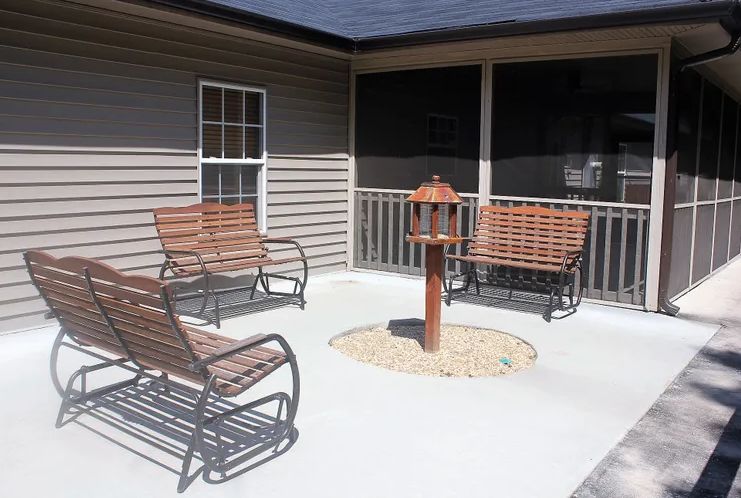 A cozy patio area featuring wooden rocking benches and a bird feeder.