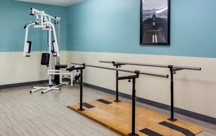 A physical therapy room equipped with parallel bars and exercise equipment for rehabilitation.