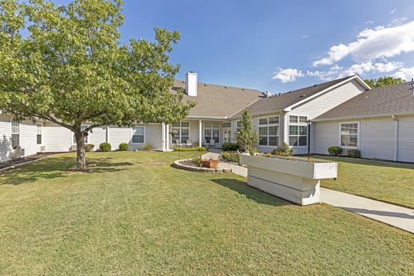 A sunny day view of a residential house with a spacious yard and garden.