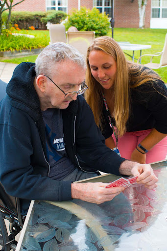 A joyful moment shared between an elderly man and a woman as they engage with a deck of cards outdoors.