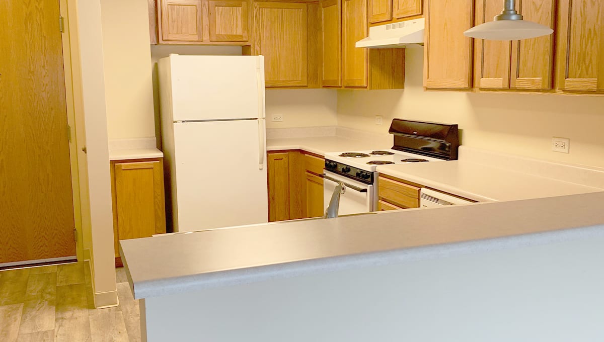 A kitchen with wooden cabinets, a white fridge, and an electric stove.