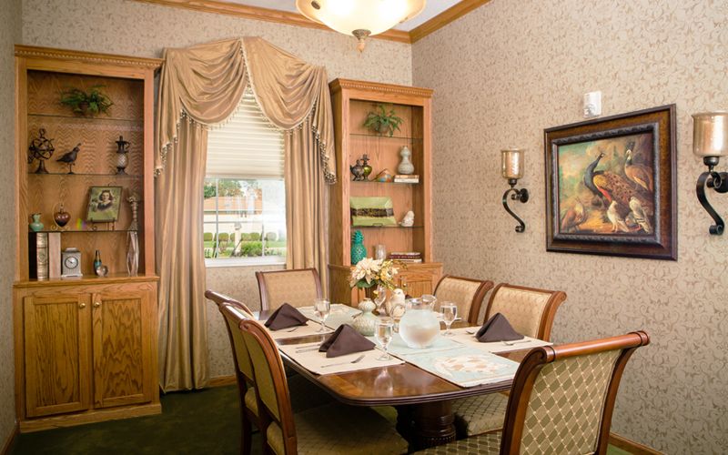 A cozy dining room with a neatly set table, elegant curtains, and tasteful decor.
