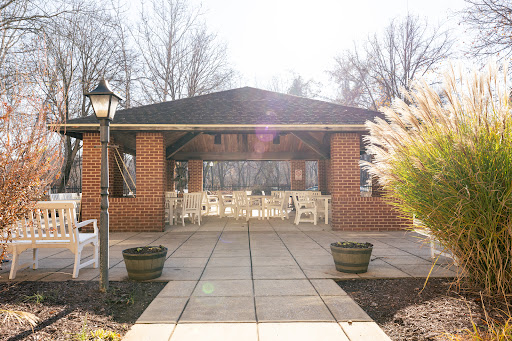 A welcoming outdoor patio with seating surrounded by lush greenery, basking in sunlight.