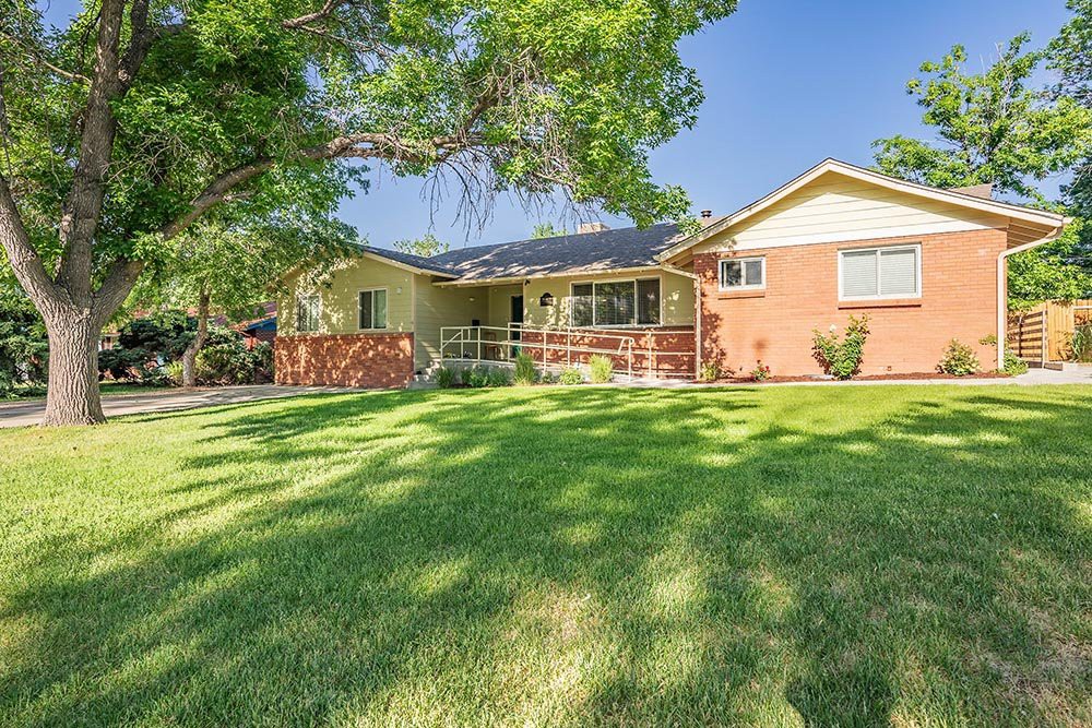 A charming ranch-style house with a well-maintained front lawn and mature trees.