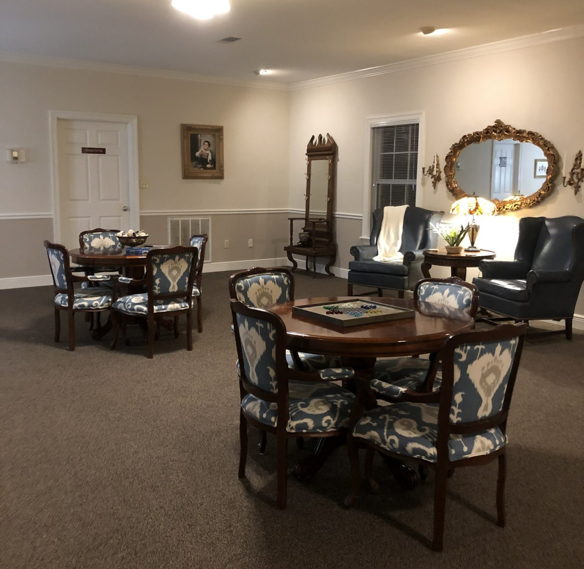 A cozy lounge area with tables, chairs, and a decorative mirror.