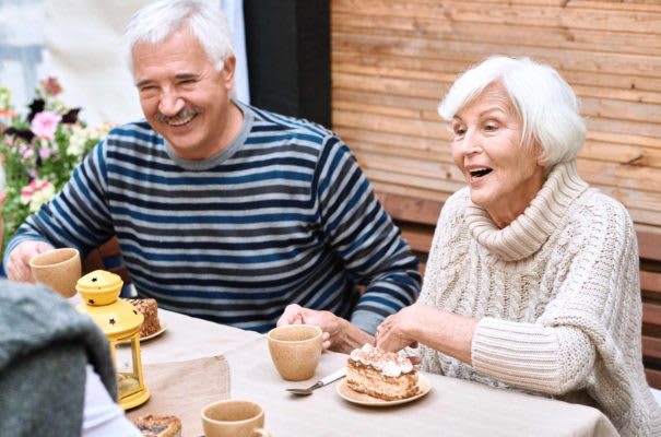 Elderly couple enjoying coffee and cake together.
