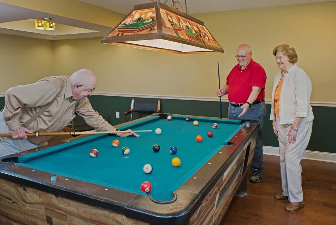 Three men enjoying a game of pool in a game room.